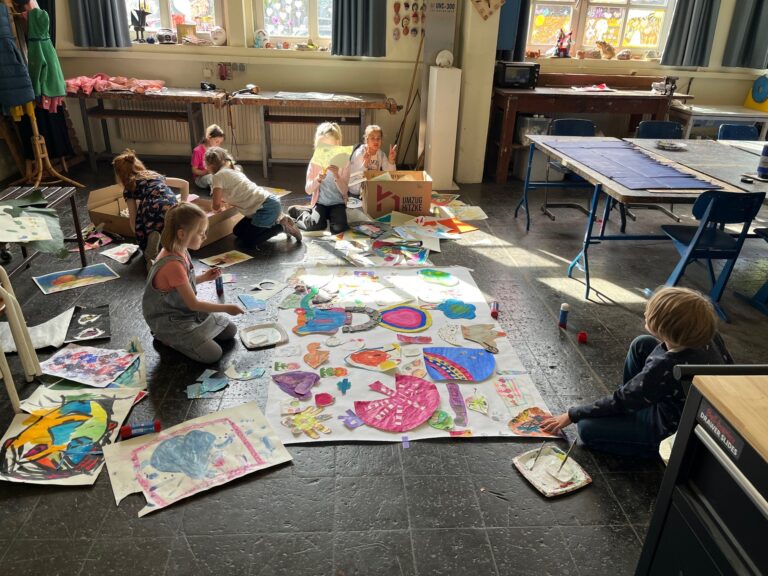 Kinder sitzen auf dem Boden mit großem Papier und erschaffen Kunstwerke