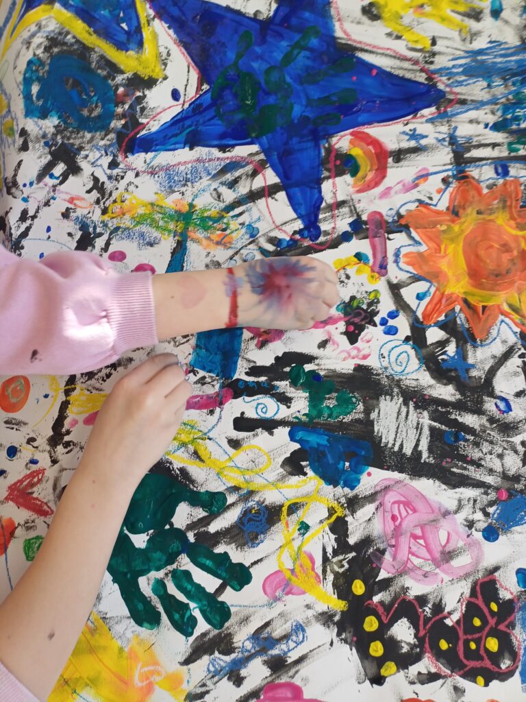 Großes Stück Papier bemalt von zwei verschiedenen Kinderhänden, bunter Style